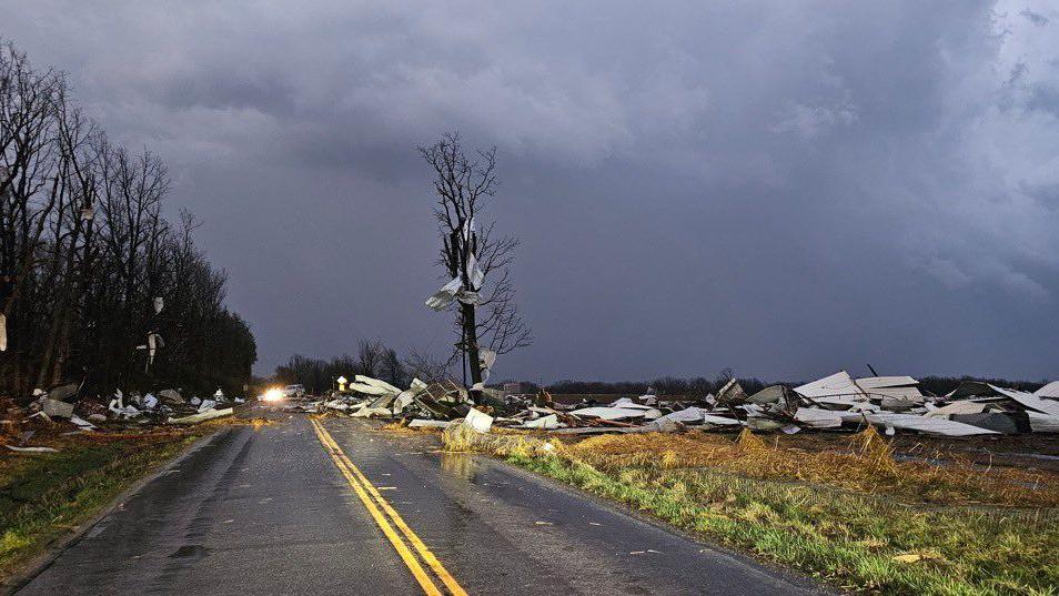 Debris strewn across a road in Missouri, with storm clouds in the background.