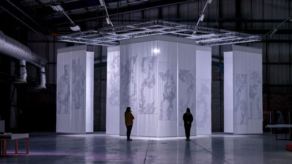 Two people look at a box-shaped exhibit at the design festival 