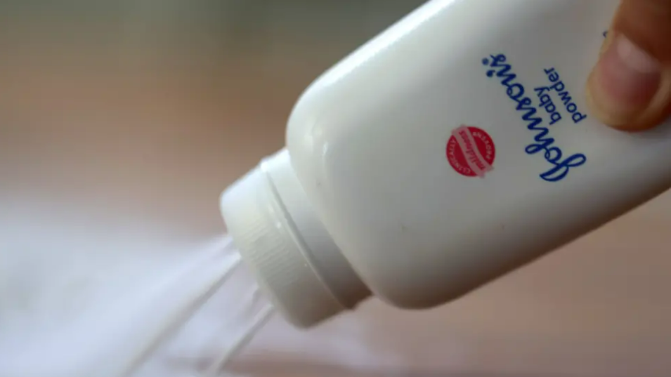 A Johnson & Johnson bottle shown pouring out talcum powder on a table