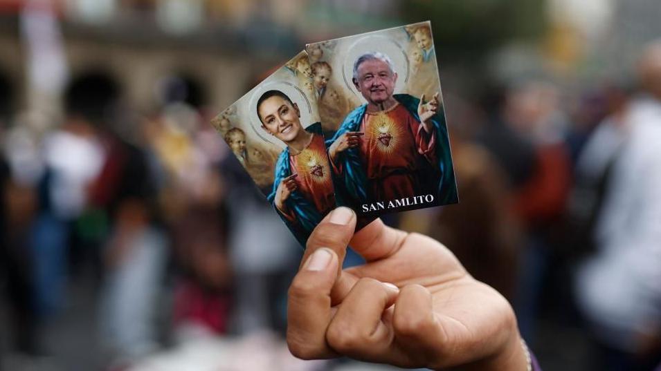 A person holds two cards with the images of Mexico's President Claudia Sheinbaum (L) and former Mexican President Andres Manuel Lopez Obrador, in Mexico City's Zocalo, Mexico, 01 October 2024.