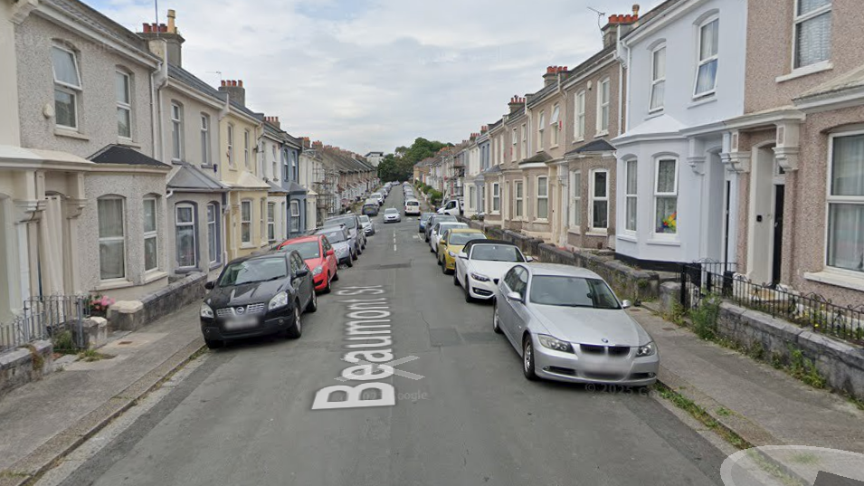 The image shows a residential street named Beaumont Street, lined with terraced houses on both sides. Several cars are parked along the street, and the houses share similar architectural styles with minor differences in colour and design.