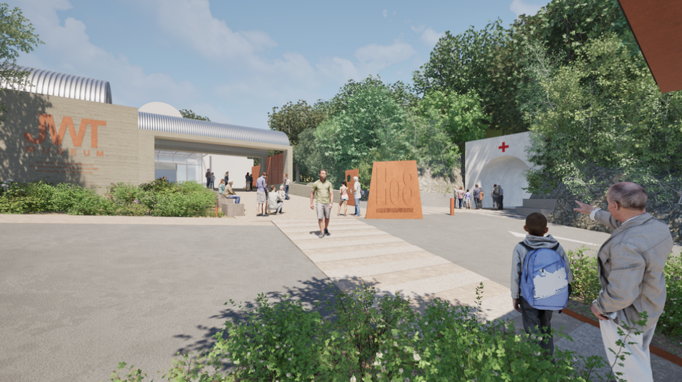 Image shows the proposed museum at Jersey War Tunnels. Pedestrians are walking around the site. A cream path leads up to the building. The side of the building has the JWT Museum logo in gold.
