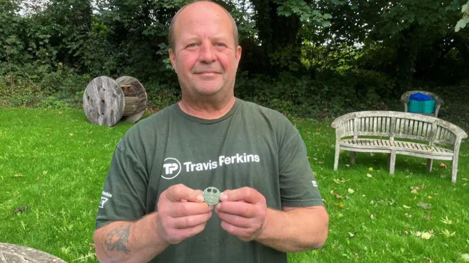 Martin stood in a garden area holding the brooch in his hand.