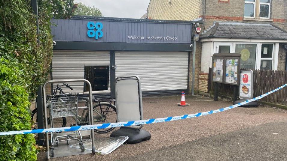 A small Co-op shop has police tape across the front. The steel shutters appear to have been cut in order to gain entry