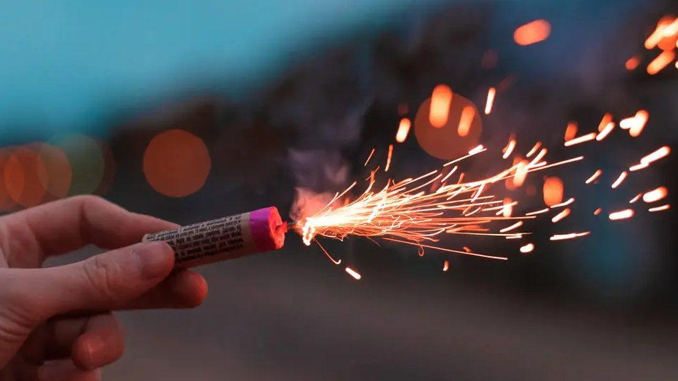 A hand holding a lit firework