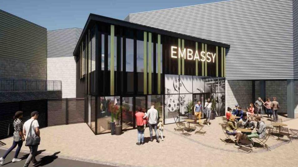 An artist's impression of the proposed northern extension of the theatre. People can be seen sitting at tables in the courtyard area. The word Embassy is prominent on the building. 