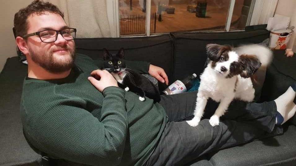 Nathan Fletcher lying on a sofa with his cat Smudge and dog Charlie.