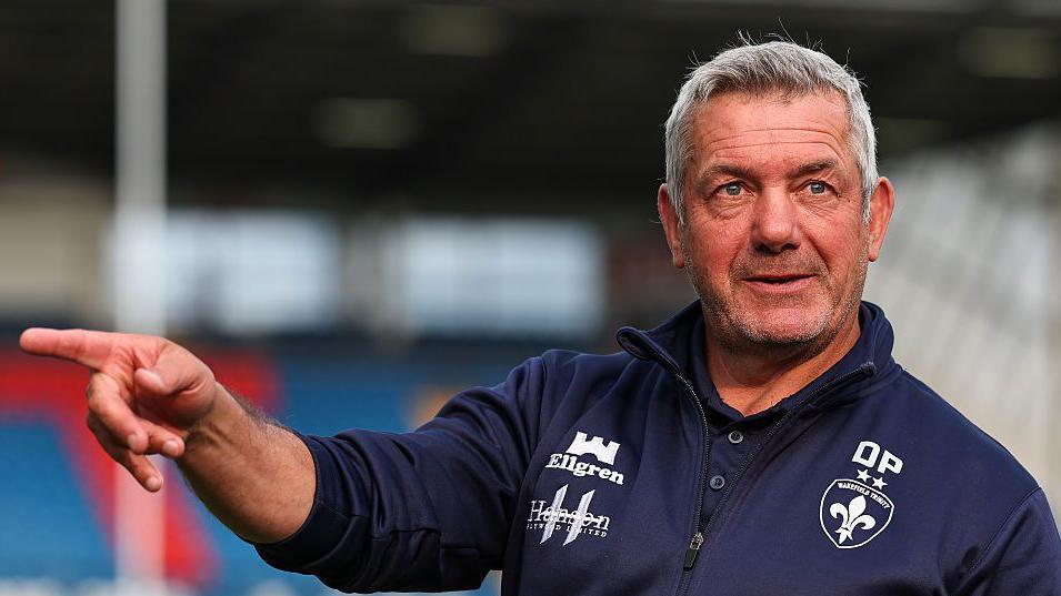 Daryl Powell directs training in a blue Wakefield Trinity top
