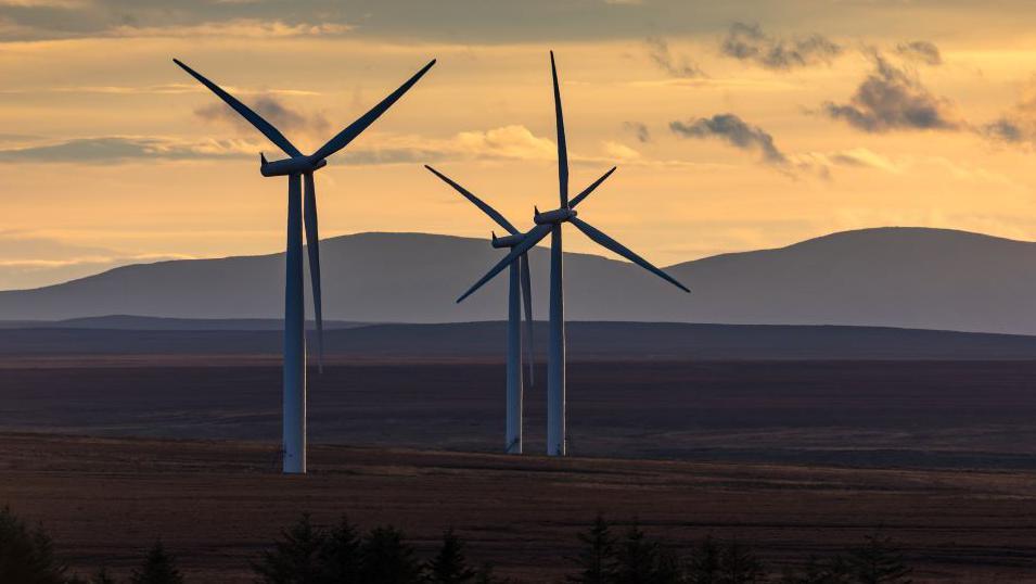 Wind turbines with hills behind them