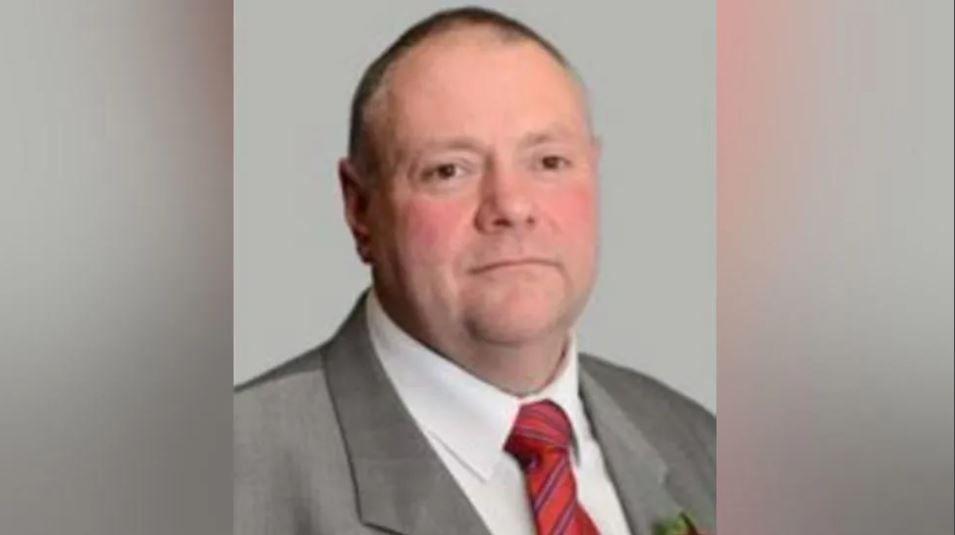 Council leader Stephen Simkins, who is wearing a grey suit jacket, white shirt and mainly red tie