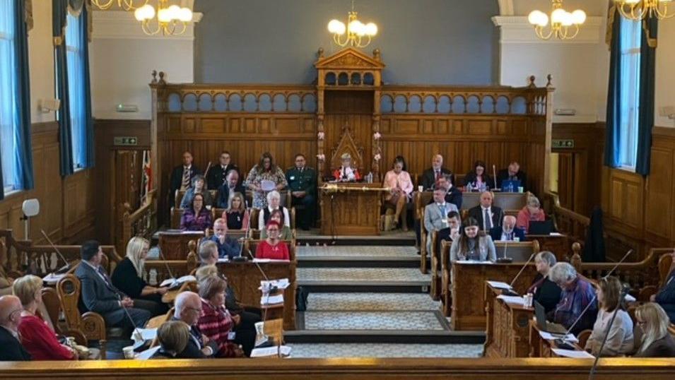 Councillors sit in silence, with heads bowed, in the council chamber as they observe a minute's silence. 