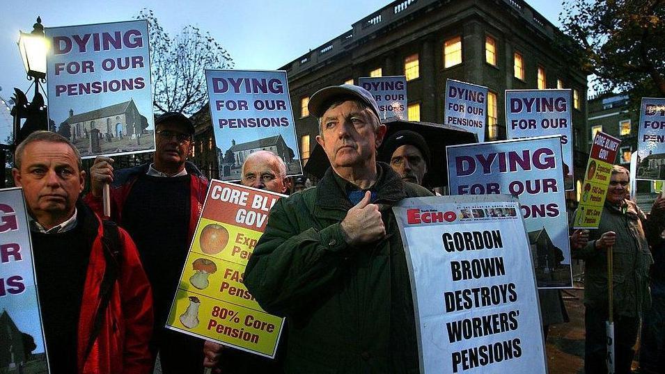 A group of men protesting in central London holding signs saying "Gordon Brown destroys workers' pensions" and "dying for our pensions".