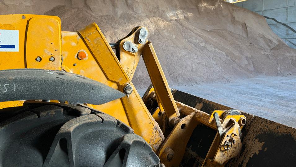 A closer view of the digger, with the mountain of salt in the distance. Its machinery is lightly caked with salt.