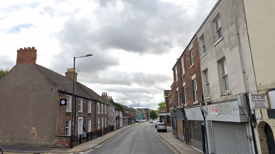 Wellowgate in Grimsby. Building line either side of the empty street and there is a silver coloured car parked on the right