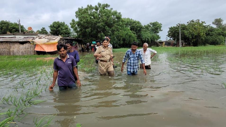 Rescue officials help evacuate people in Surajgarh village of Nalsarovar area  as flood waters rise above the knee