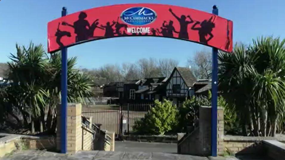 The entrance sign to the former Pleasure Island with steps going down, trees either side and old buildings in the distance 