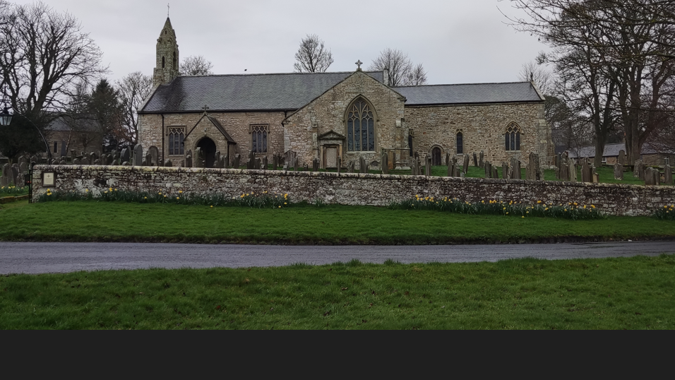 A 14th century church with daffodils outside 