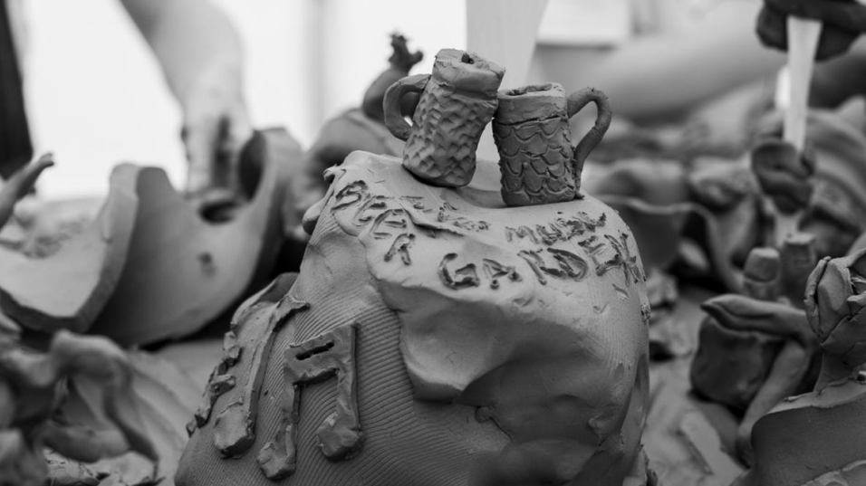 A pile of clay with music notes on the side and writing on the top and two beer cups on the top. 