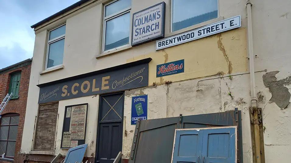 Part of the Bodies film set, showing an old fashioned shop with vintage signs and advertisements. 