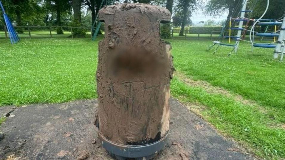 Mud smeared over a bin in Wigton Park. A blurred-out expletive has been written on it.