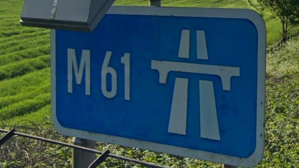 Motorway sign for the M61with green fields in the background