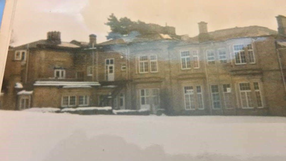 Shotley Park in the 1970s. The two-storey stone building is surrounded by snow.  It has large windows with white panes. 