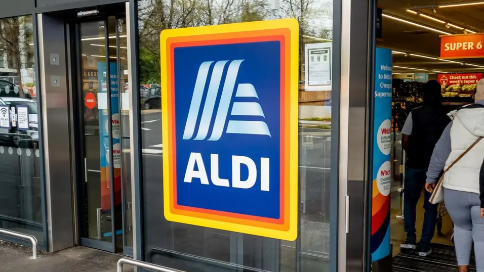 The front entrance to a branch can be seen with the shop's logo on a glass door and shoppers inside.