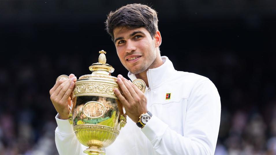 Carlos Alcaraz holds up the Wimbledon men's singles trophy after winning the 2024 final