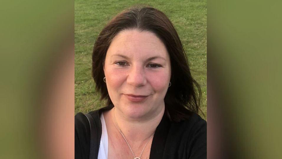 Kirsty Knight smiling for the camera in a selfie, wearing a black cardigan.