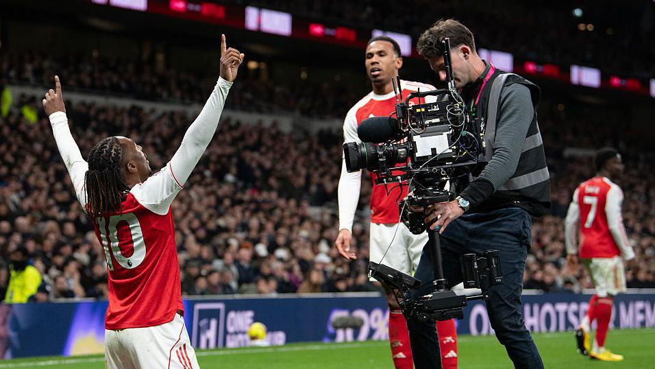A cameraman films Arsenal's Eberechi Eze as he celebrates scoring a goal