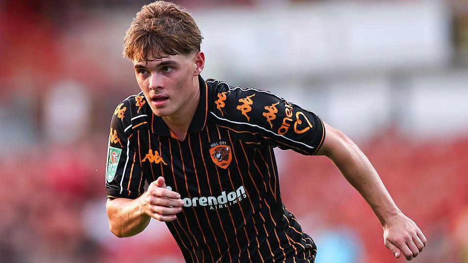Hull City midfielder Nathan Tinsdale in the club's black with gold pinstripe shirt.