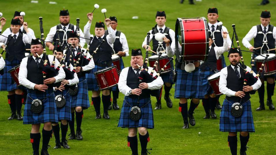Pipe band members wearing dark blue kilts compete