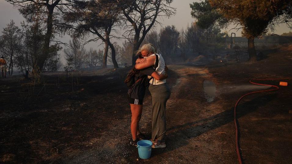 Marina Kalogerakou, 24, hugs her aunt Eleonora Zoakou, 48, as a wildfire burns in Penteli, Greece, August 12, 2024