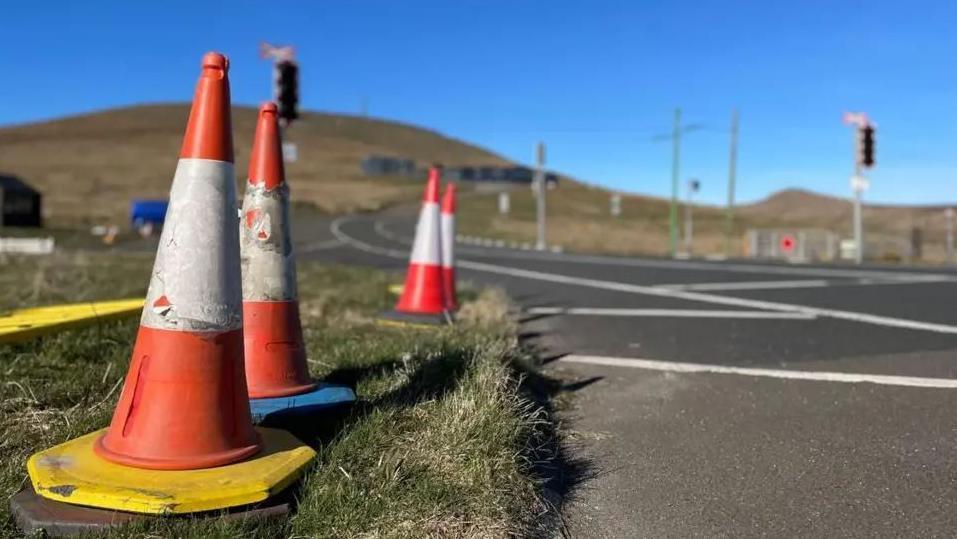 Traffic cones on the side of the road at the Bungalow on the Mountain Road with Snaefell Mountain is in the background.