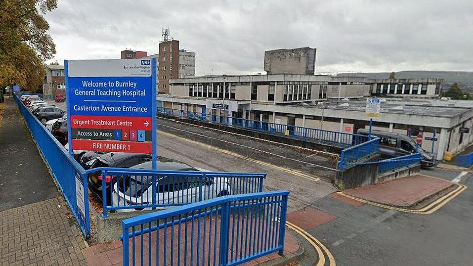 External view of the entrance and sign which reads 'Burnley General Teaching Hospital' showing vehicle parked outside the main building