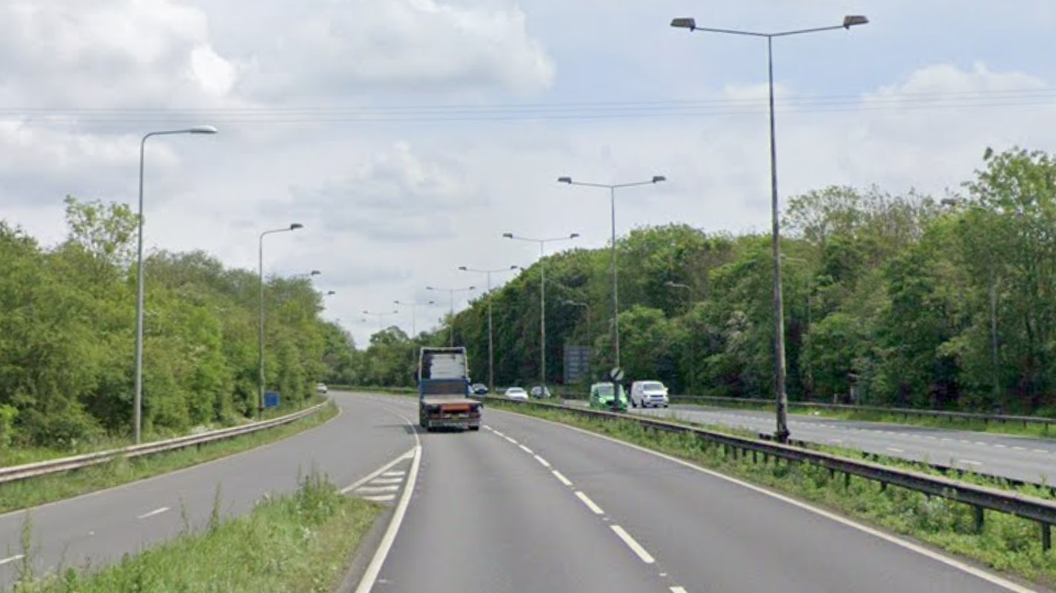 A dual carriageway with a junction joining the road to the left hand side, a lorry up ahead and vehicles on the opposite carriageway