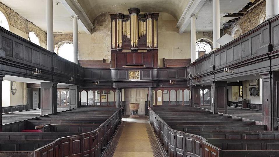 General view of interior showing nave box pews in oak arranged in 2 double rows and organ with its original mahogany case.