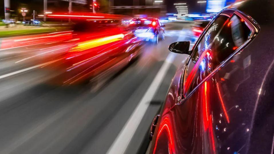 A stock image of a car travelling at speed next to a car sat in traffic.