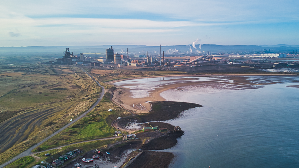 Overhead shot of coast and lots of factories near green land.