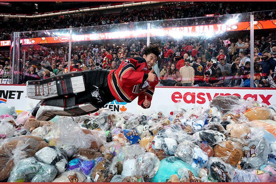 An ice hockey goalie leaps on to a pile of stuffed toys during a charity event on the rink