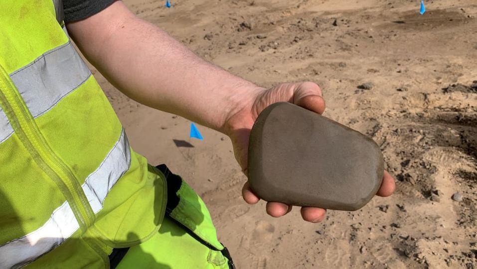 An archaeologist holding a whetstone