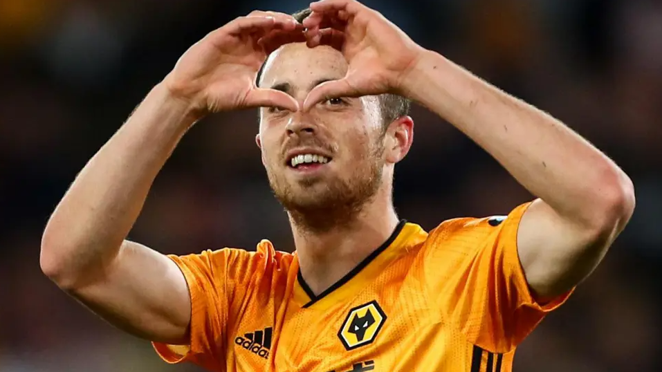 Diogo Jota with short brown hair in a yellow and black Wolves football kit making a heart symbol with his hands and smiling.