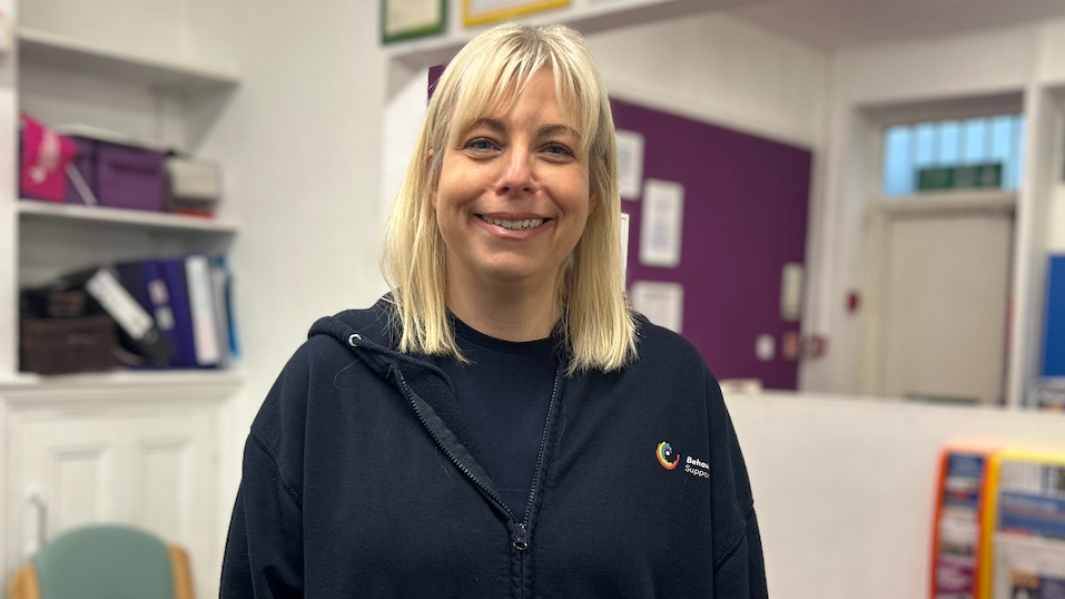 Beth Tingle mewn siwmper ddu a gwallt melyn yn gwenu
