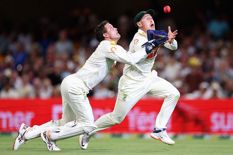Alex Carey and Marnus Labuschagne dive simultaneously to catch the ball with the crowd in the background