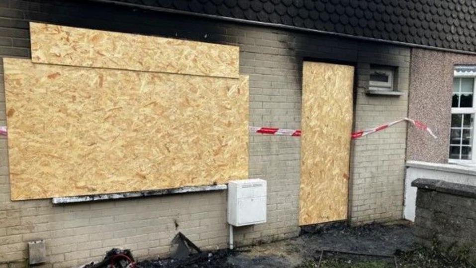 a house badly damaged by fire in Derry with windows boarded up