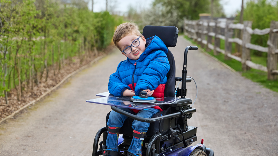 Jon's son Ethan wearing a blue coat in his electric wheelchair
