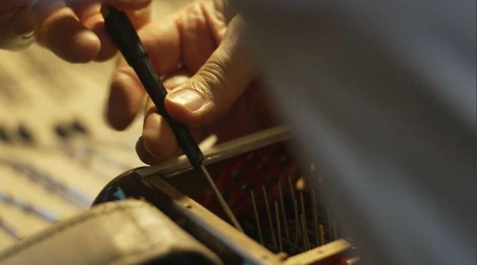 Hands using a tool work on an accordion