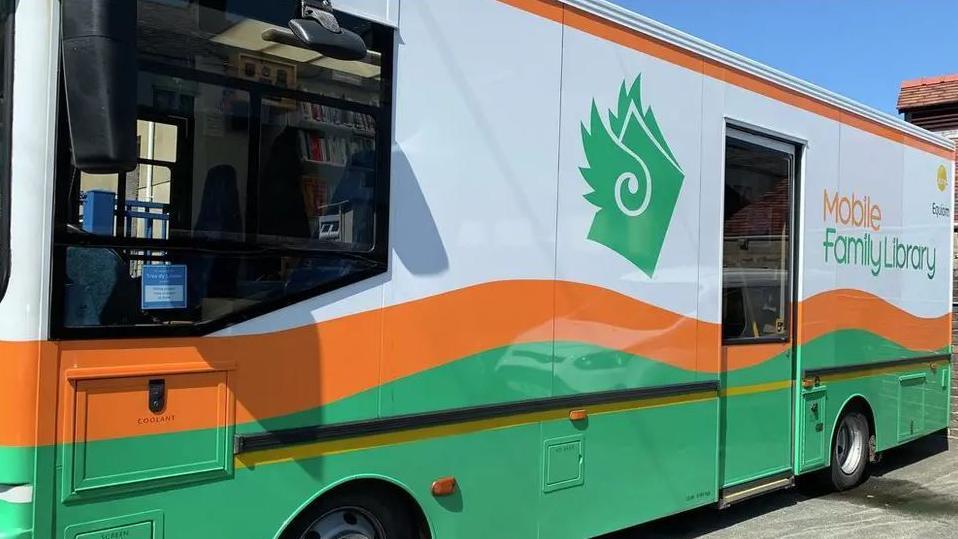 An orange, green and white bus with mobile family library written on the side.
