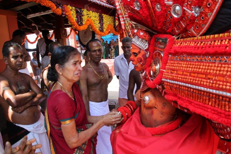 A woman shakes the hand of a man wearing an elaborate red headdress