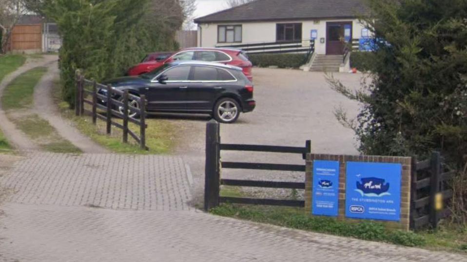 An RSPCA building in the country. The RSPCA sign is on a wall in front of a car park boarded by wooden fences.